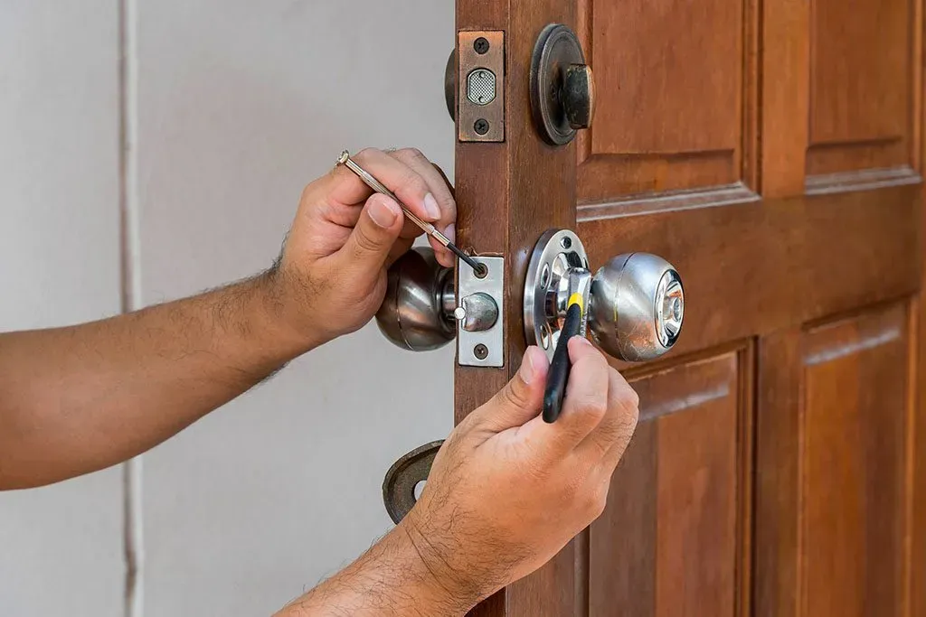 Handyman repairing a garage door lock with tools, showcasing EcoStar Garage Doors' expert services in Kansas City.
